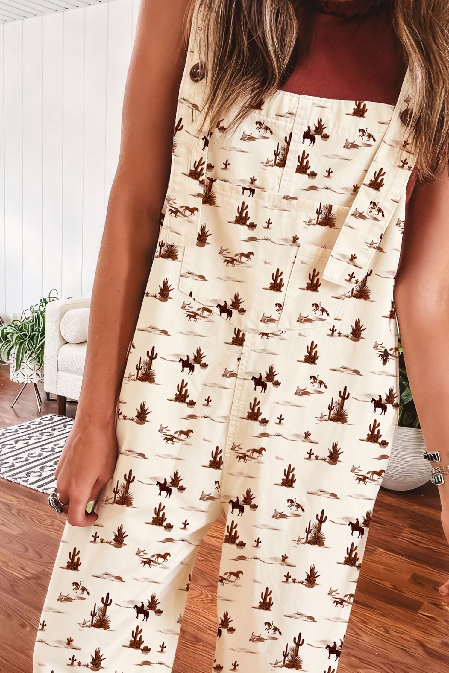 Person wearing a western cowboy desert patterned jumpsuit with a desert design standing indoors